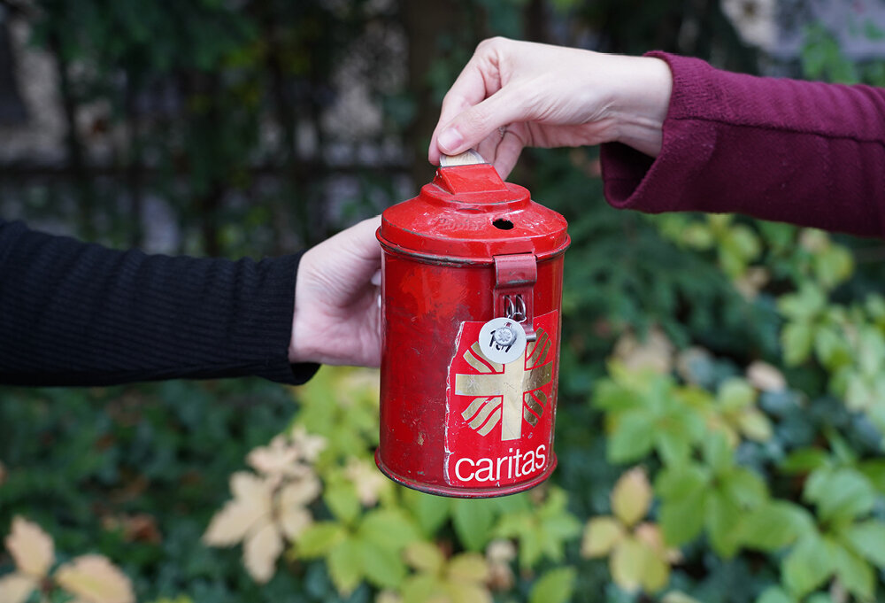 Eine rote Sammelbüchse in die Geld eingeworfen wird | © Caritasverband München und Freising e.V.