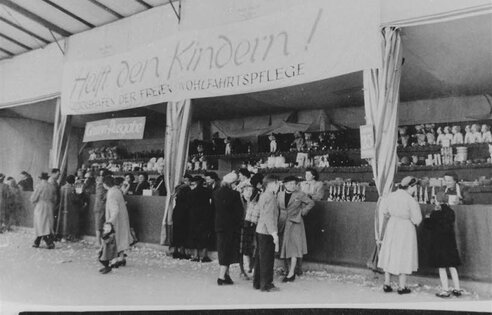 Glückshafen-Stand der freien Wohlfahrtspflege auf dem Münchner Oktoberfest, 1956. | © (Fotograf unbekannt, Archiv des DiCV München und Freising e. V., Fotosammlung)