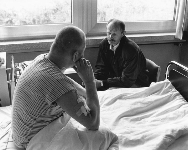 Gespräch eines Klinikseelsorgers mit einem Patienten, ca. 1990. | © (KNA, Archiv des DiCV München und Freising e. V., Fotosammlung)
